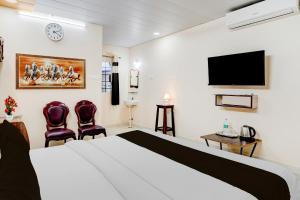 a hotel room with a bed and two chairs at Super Hotel O Chittoor Railway Station Formerly Four Oaks in Chittoor +22 photos