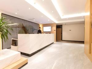 a man standing at a counter in a lobby at Green Tree Inn Nanchang Zhongshan Road Bayiguan in Nanchang