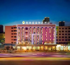 Un gran edificio rosa con escritura en el costado. en GreenTree Inn Express Datong High-Speed Railway Station Old City Wall, en Datong