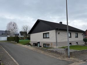 ein weißes Haus mit einem schwarzen Dach auf einer Straße in der Unterkunft Ferienwohnung am Ith in Eschershausen