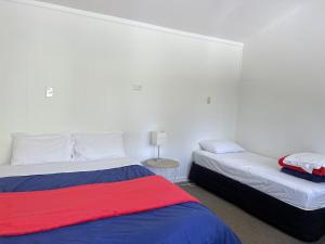 ワナカにあるMt Aspiring Holiday Parkのベッドルーム1室(ベッド2台、ランプ付きテーブル付)