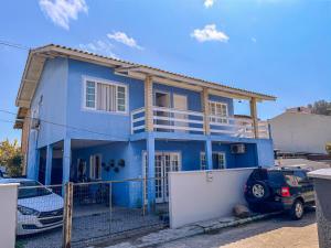 een blauw huis met een auto ervoor geparkeerd bij Apartamento 1 Quarto Canasvieiras in Florianópolis