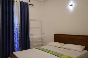 een slaapkamer met 2 bedden en een raam met blauwe gordijnen bij Villa Hideout in Unawatuna