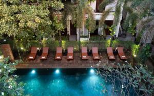um grupo de cadeiras ao lado de uma piscina em The Moon Residence & Spa em Siem Reap