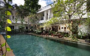 a swimming pool in front of a building with trees at The Moon Residence & Spa in Siem Reap