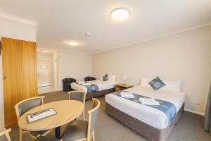 una habitación de hotel con dos camas y una mesa en Esplanade Hotel Busselton, en Busselton