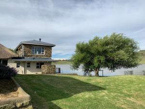 een huis met een boom voor een meer bij The Boathouse in Harrismith