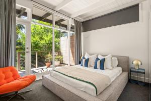 Clarevilleにある'Rosella' A Mid Century Modern House, Avalon Beachのベッドルーム(大型ベッド1台、オレンジ色の椅子付)