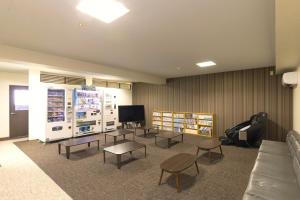 a waiting room with tables and chairs and a tv at カプセルホテルグロリア in Beppu