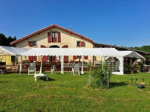 Zelt vor einem Gebäude mit Tischen und Stühlen in der Unterkunft ENTRE ADOUR et MONTAGNE in Pouillon