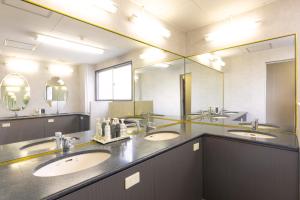 a bathroom with three sinks and a large mirror at カプセルホテルグロリア in Beppu