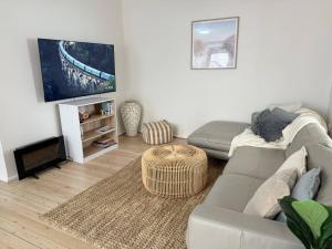 a living room with a couch and a tv at Stunning Ground Floor Apt with Ocean Views in Cronulla +14 photos