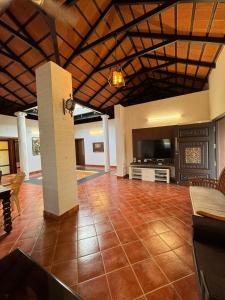 Una sala de estar con suelo de baldosas y televisión. en Chettinadu Pool Villa, en Pollachi