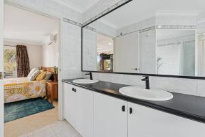 un baño con dos lavabos y un espejo en Its Hugo Cottage, en Truganina