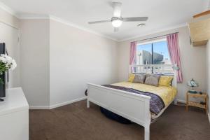 Un dormitorio con una cama blanca y una ventana. en Its Hugo Cottage, en Truganina