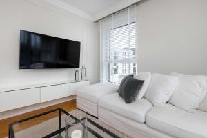 a white living room with a white couch and a tv at Elegant Apartment with Parking Space and Balcony by Noclegi Renters in Gdynia +15 photos