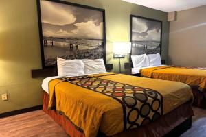 2 letti in una camera d'albergo con dipinti alle pareti di Super 8 by Wyndham Jackson Ridgeland a Jackson Altre 60 foto