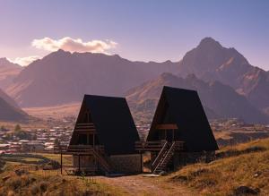 two buildings on a hill with mountains in the background at Arsha View in Kazbegi