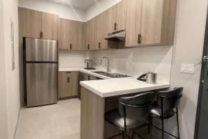 a kitchen with a stainless steel refrigerator and two bar stools at La Quinta Inn & Suites by Wyndham Kelowna BC in Kelowna
