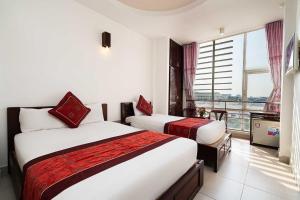 a hotel room with two beds and a balcony at Collection O Dinh Dinh Hotel - Near Tan Son Nhat Airport in Ho Chi Minh City