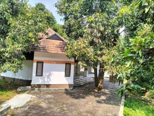 a small white house with trees in front of it at BharathaPuzha Villa in Kārakkād