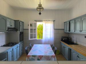 a kitchen with blue cabinets and a table and a window at Location saisonnière Chez Paulette in Cilaos