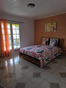 a bedroom with a bed in a room with a window at Location saisonnière Chez Paulette in Cilaos