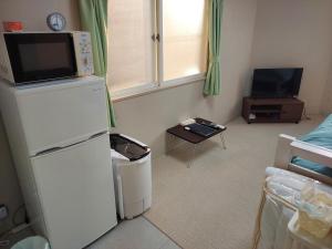 Una sala de estar con refrigerador y televisor. en トリトン茶屋町#201#202, en Aomori