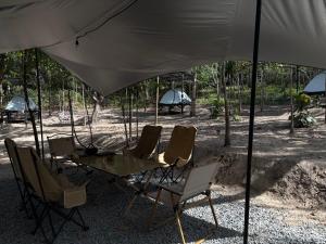 une table et des chaises sous un parasol blanc dans l'établissement Ko Kut Nature Camp, à Ko Kood