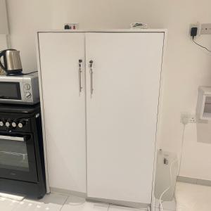 une armoire blanche dans une cuisine à côté d'un micro-ondes dans l'établissement PONTOOn STUDIO, à Mombasa