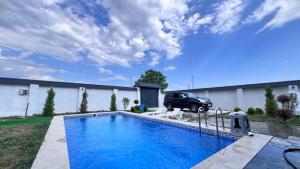 een groot blauw zwembad in een tuin met een auto bij Gabala Garden & Mountain View Villa in Gabala