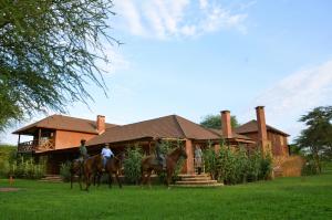 two people riding horses in front of a house at Kili Villa Kilimanjaro Luxury Retreat in Arusha