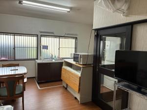 a room with a kitchen with a tv and a table at Ogoto House Rake Omi in Otsu
