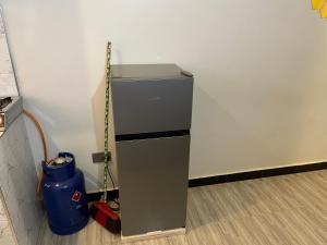 a small refrigerator in a room with a bucket at Zuri stays in Kampala