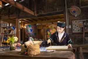 a woman is writing on a book on a table at PaoDzung homestay Tả Van in Sa Pa