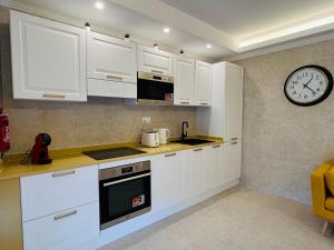 ビルキルカラにあるRosalina Residencesの白いキャビネットと壁掛け時計付きのキッチン