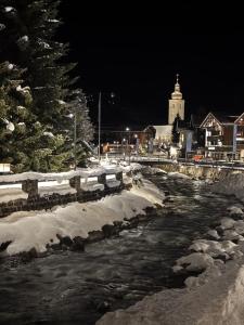 a river with snow on the banks at night at Apartment Chalet Ambros in Lech am Arlberg
