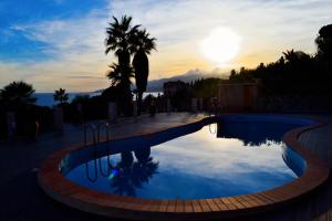 a swimming pool with a sunset in the background at Sicily in Villa in Messina