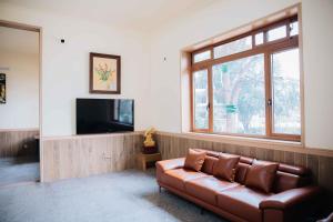 een woonkamer met een leren bank en een televisie bij Baviecoresort in Ba Vì