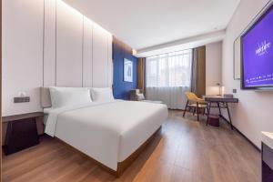 una camera d'albergo con letto bianco e schermo per proiezione di Mercure Jinan Beiyuan Street a Jinan