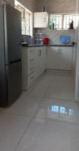 eine Küche mit weißen Schränken und einem Edelstahlkühlschrank in der Unterkunft Ps House in Gaborone