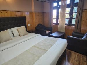a bedroom with a large bed and two chairs at Veronica Alpina Mountain View Home in Darjeeling