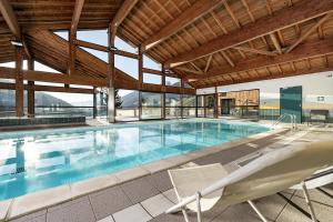 a large swimming pool in a building with a large ceiling at Chalet Valora in Le Grand-Bornand