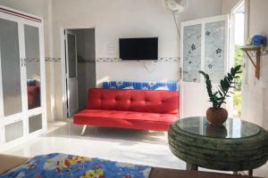 eine rote Couch in einem Wohnzimmer mit einem Tisch in der Unterkunft Vườn Dừa Cam Bình 1 in La Gi
