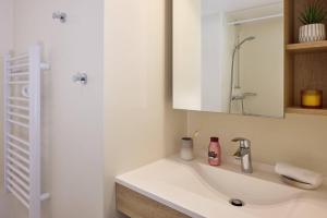 Un baño blanco con lavabo y espejo. en Zenitude Quality Aparthotel Plerin, en Plérin 31 fotos más