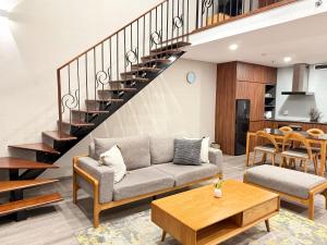 a living room with a couch and a staircase at PentStudio Westlake - Cozy Duplex Apartment in Hanoi