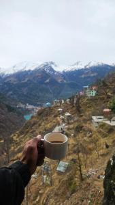 a person holding a cup of coffee on a mountain at Hill Ice Guesthouse in Tosh