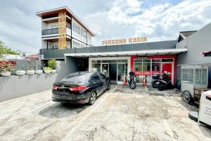 a car parked in a parking lot in front of a dealership at Perdana Kasih Hotel Pemuda Klaten Mitra RedDoorz in Solo
