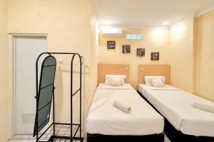 a room with two beds and a mirror at Perdana Kasih Hotel Pemuda Klaten Mitra RedDoorz in Solo