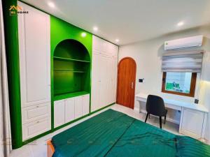 - une chambre avec des murs verts, un lit et un bureau dans l'établissement Bi Home, à Phú Mỹ 2 autres photos